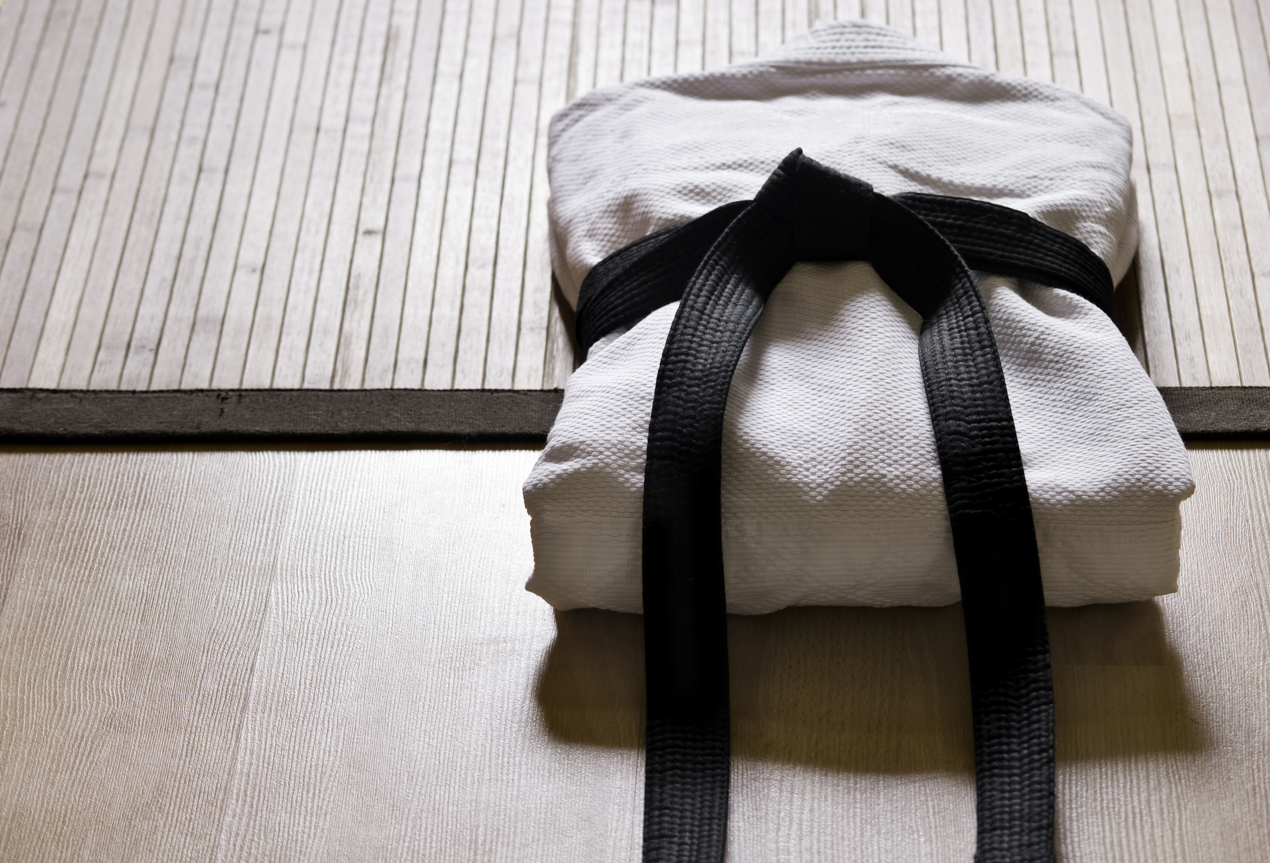 Folded judo gi with black belt on tatami mat. Martial arts training for business success!