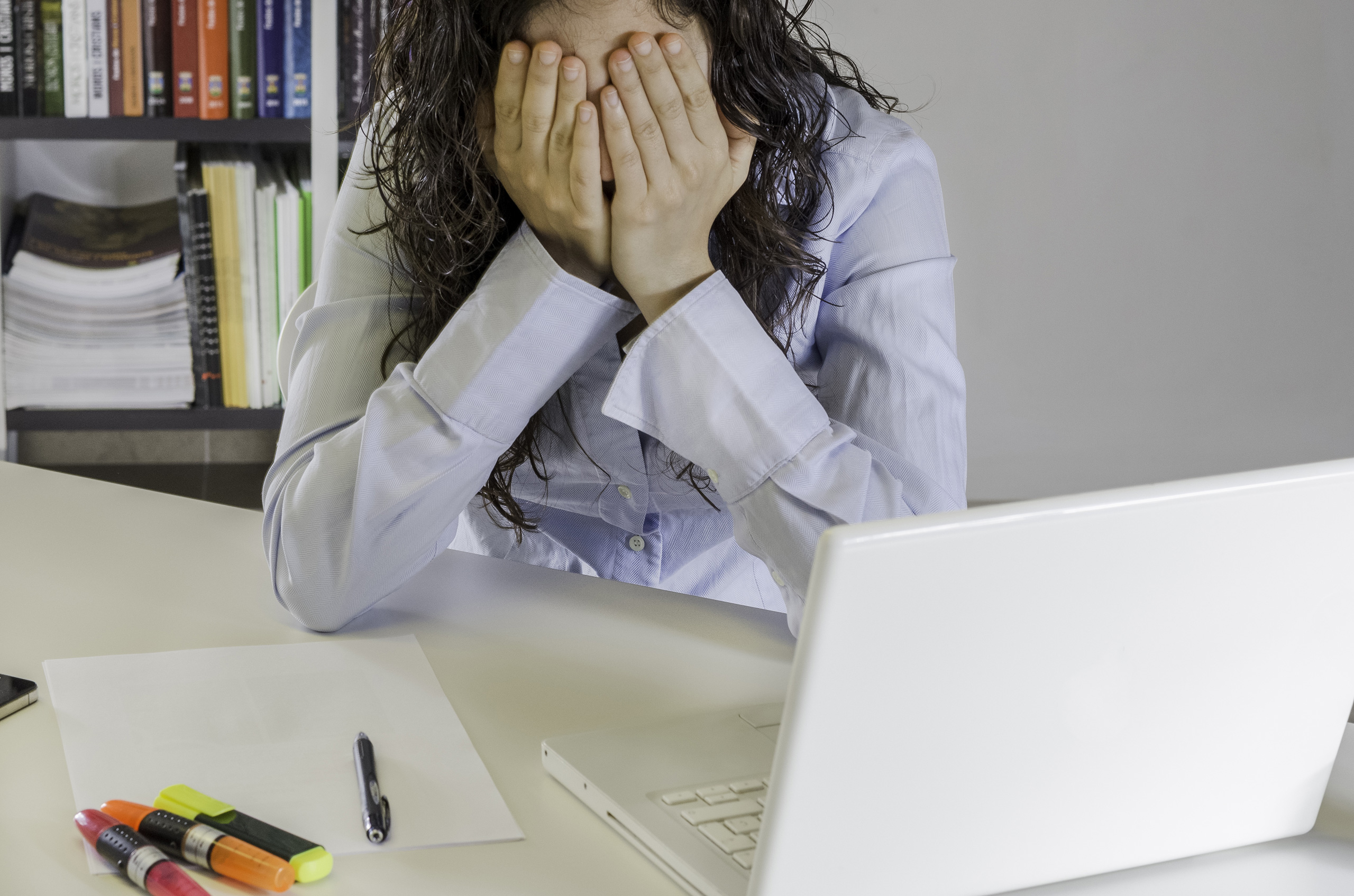 Woman with head in hands at desk with laptop. Feeling low energy? Read blog now!