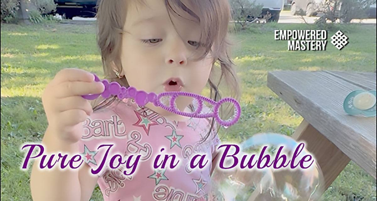 Little girl blowing bubbles with a purple wand, "Pure Joy in a Bubble.